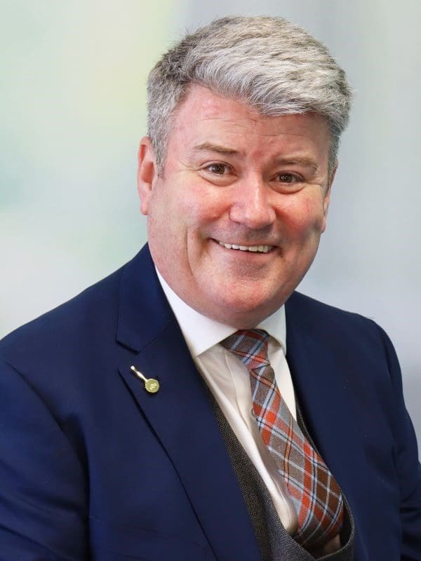 Paul Gilhooly's corporate headshot, featuring the Disciples Escoffier pin on his lapel.